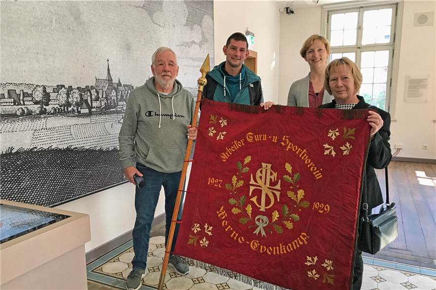 Schatz aus dem Keller: Eintracht Werne übergibt Stadtmuseum eine echte Rarität Mehrere Menschen halten eine alte Fahne.