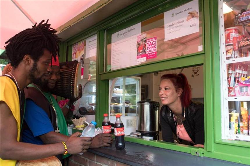 Musiker Nii Okine Mettlz (l) und Natty Marbell erfrischen sich gern mit einem Getränk vom Grünen Büdchen in Duisburg, wo sie von Jaqueline Wolf bedient werden. Foto: Federico Gambarini