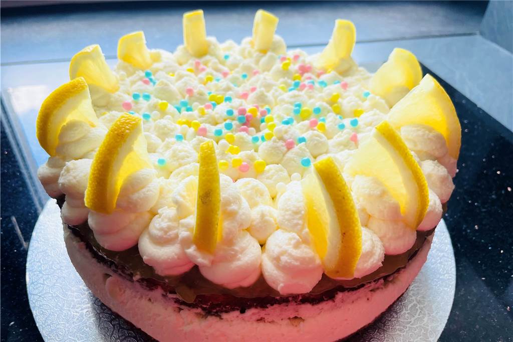 Fruchtig frische Buttermilch-Zitronen-Torte schmeckt nach Sommer Nach Belieben dekorieren. Hier: frische Zitrone und Dekorperlen.