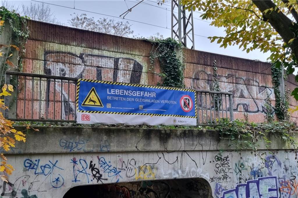 Ein Warnplakat zur Lebensgefahr im Gleisbett hängt an der Bahnstrecke in Dortmund-Dorstfeld