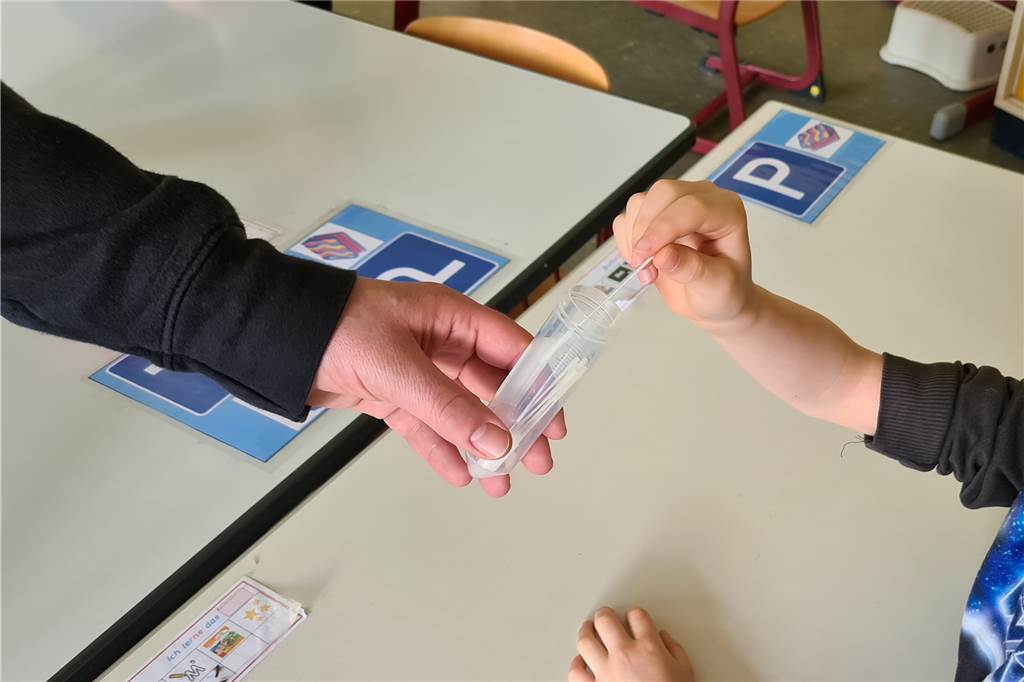 Osterfeldschule Lünen: Lolli-Tests werden Routine für Erstklässler Nach dem Test stecken die Schülerinnen und Schüler der Osterfeldschule in Lünen das Stäbchen mit der Probe in einen Sammelbehälter.