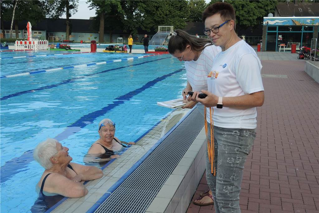 Wegen Corona: Sportabzeichen in Castrop-Rauxel mal anders - und doch wie immer Nach der Leichtathletik-Stunde an der Uferstraße ging es beim Sportabzeichen im Parkbad Nord in Ickern weiter. Hier war es die Aufgabe von Ute Spengler (r), die Schwimm-Zeiten zu messen, auch von Frauke Hein (im Wasser rechts). Ihr Ziel ist es, zum 60. Mal erfolgreich die Prüfungen zu schaffen.
