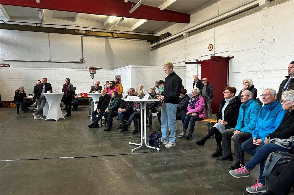 Menschen sitzen in einer Fabrikhalle.