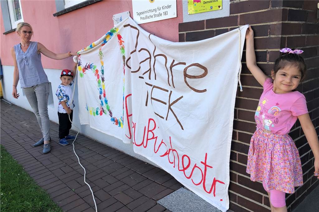 Viel zu tun für Nadine Büth - einstiger Zechenkindergarten wird 50 Jahre alt Nadine Büth sowie die Kinder Aras und Zeynep zeigen ein großes Plakat, das die Kindergartenkinder zum 50-jährigen Bestehen der Einrichtung gebastelt haben