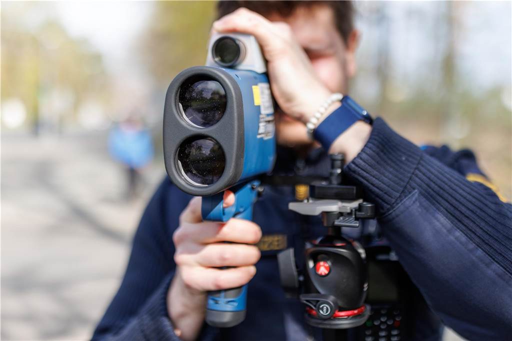 Ein Polizist schaut durch ein Laserhandmessgerät.