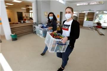 Neubau des Kindergartens „Unter dem Regenbogen“: Beim Umzug tragen Leiterin Silvia Oeste (r.) und Erzieherin Eugenia von der Heide Kisten mit Spielsachen in die neuen Räume.