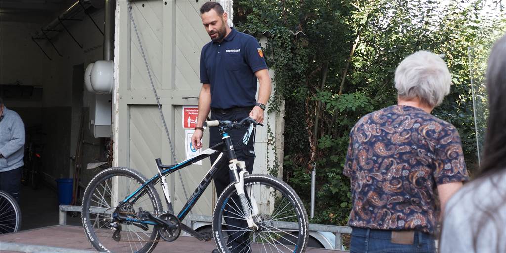 Ehering, Wodkaflasche und plattes Rad: Stadt Selm versteigert Fundsachen Ein Mann steht mit einem Fahrrad, das versteigert werden soll, auf einer Art Bühne.