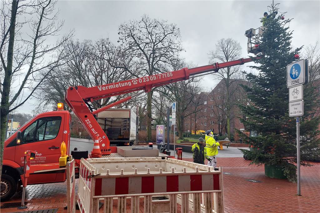 Ein Mitarbeiter auf einem ausfahrbaren Kran montiert die Deko eines Weihnachtsbaums in der Lüner Innenstadt ab.