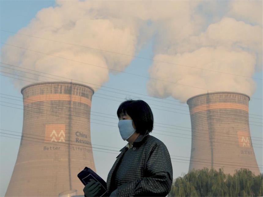 «New York Times»: Chinas CO2-Ausstoß viel höher als gedacht Nicht ohne Maske: Eine Anwohnerin geht am Kühlturm eines Kohle-Heizkraftwerks in Shenyang im Nordosten Chinas vorbei. Foto: Mark/Archiv