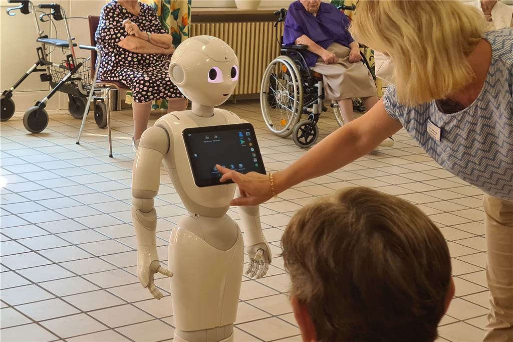 Nicole Wähning, Koordinatorin Sozialer Dienst im Evangelischen Altenzentrum Lünen, bedient Pepper über einen integrierten Tablet-PC. Sie kann einstellen, welche Handlungen der Roboter durchführen soll.