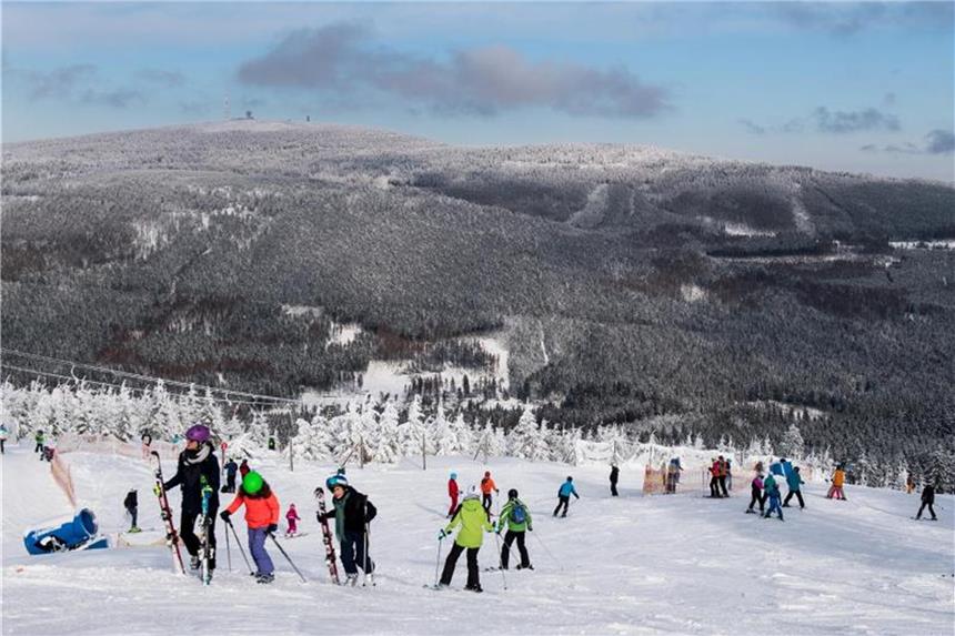Einige Wanderwege im Harz durch Sturmschäden gesperrt Niedersachsen, Braunlage: Ski- und Snowboardfahrer fahren auf dem Wurmberg im Oberharz einen Abhang vor der Kulisse des Brockens hinunter. Foto: Swen Pförtner/dpa