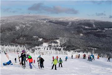 Niedersachsen, Braunlage: Ski- und Snowboardfahrer fahren auf dem Wurmberg im Oberharz einen Abhang vor der Kulisse des Brockens hinunter. Foto: Swen Pförtner/dpa