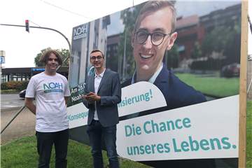 Der Dortmunder parteilose Bundestagskandidat Noah Trojanowski (r.) mit Vincent, einem Freund und Wahlkampfhelfer, vor seinem Großplakat an der B1.