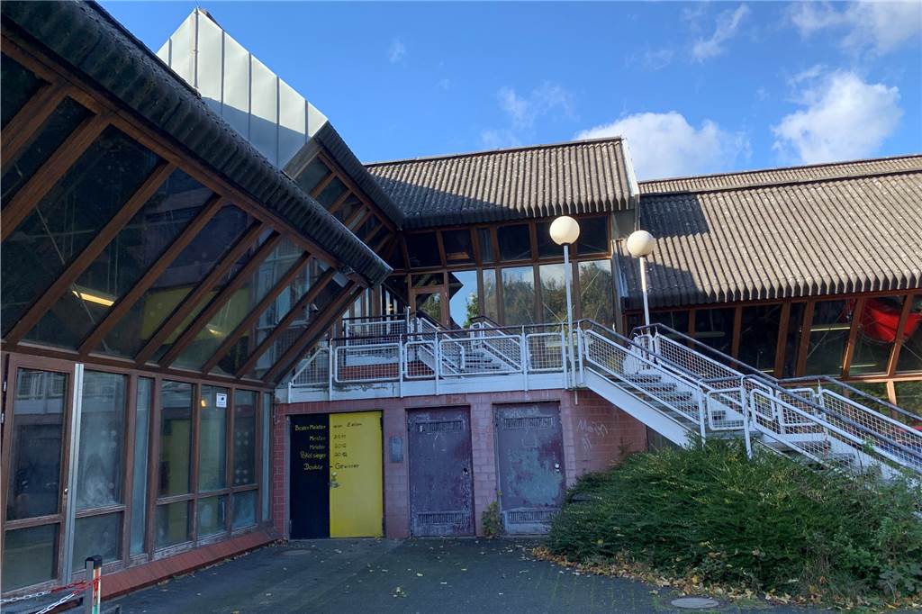 Das sanierungsbedürftige Westbad in Dorstfeld: Links große Fensterscheiben, durch die man die Schwimmbecken sehen kann, in der Mitte Treppen.