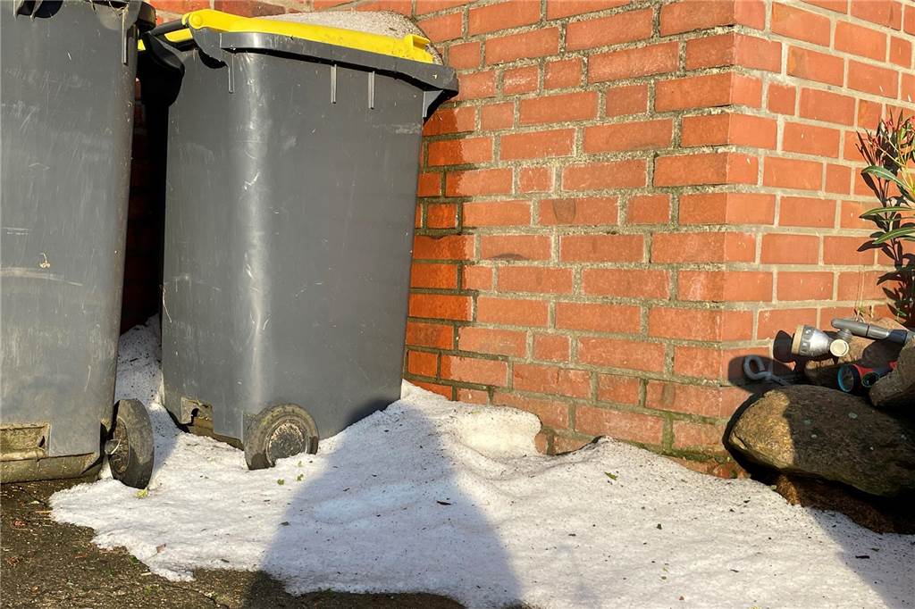 Hagel hinterlässt Schneise der Verwüstung: Schäden in Getreide und Mais Ein Hagelhaufen neben Mülltonen.