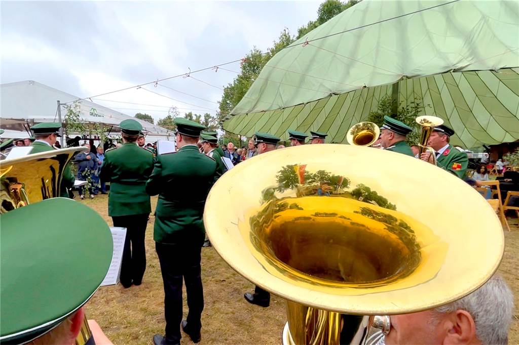Blick über eine Tuba der städtischen Kapelle auf die feiernden Schützen