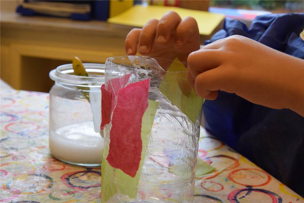 Till (5) zeigt uns, wie man eine bunte Last-Minute-Laterne bastelt Nun wird das bunte Papier auf dem Kleister befestigt.