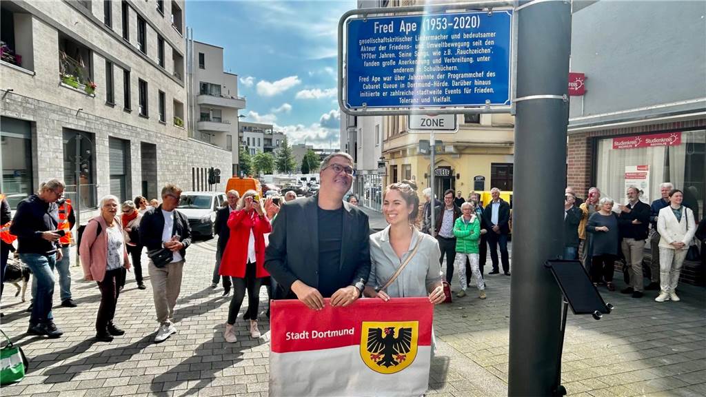 Emotionale Enthüllung des Fred-Ape-Legendenschildes mitten in Hörde Nur eine Lichtbrechung oder vielleicht doch ein Zeichen von oben? Ein Lichtstrahl fällt genau auf Fred Apes Tochter. Im Hintergrund das Queue.