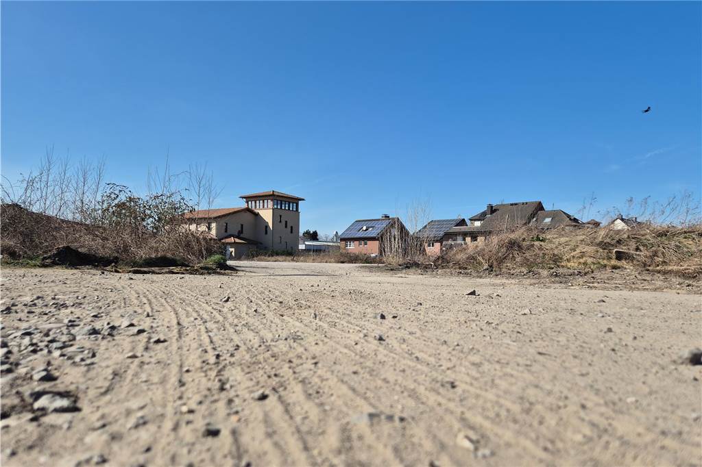 Trockener Boden Sand kies im Hintergrund Häuser mit blauem Himmel