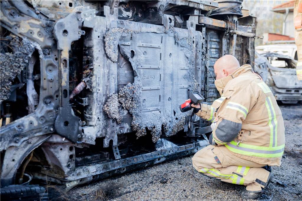 Acht Mythen über E-Autos - und was Experten dazu sagen Ein Feuerwehrmann untersucht ein ausgebranntes E-Fahrzeug.