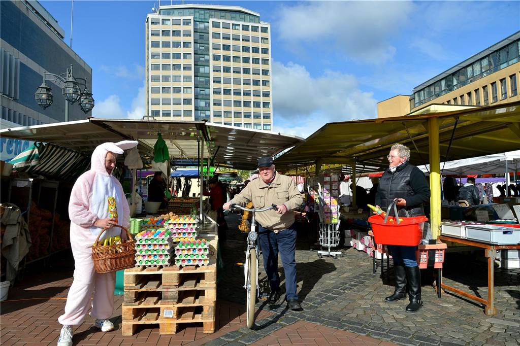 Lebensgroßer Osterhase steht vor Eier-Paletten. 
