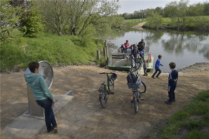 Menschen stehen am Ufer der Lippe und warten auf das Anlegen der Kurbelfähre.