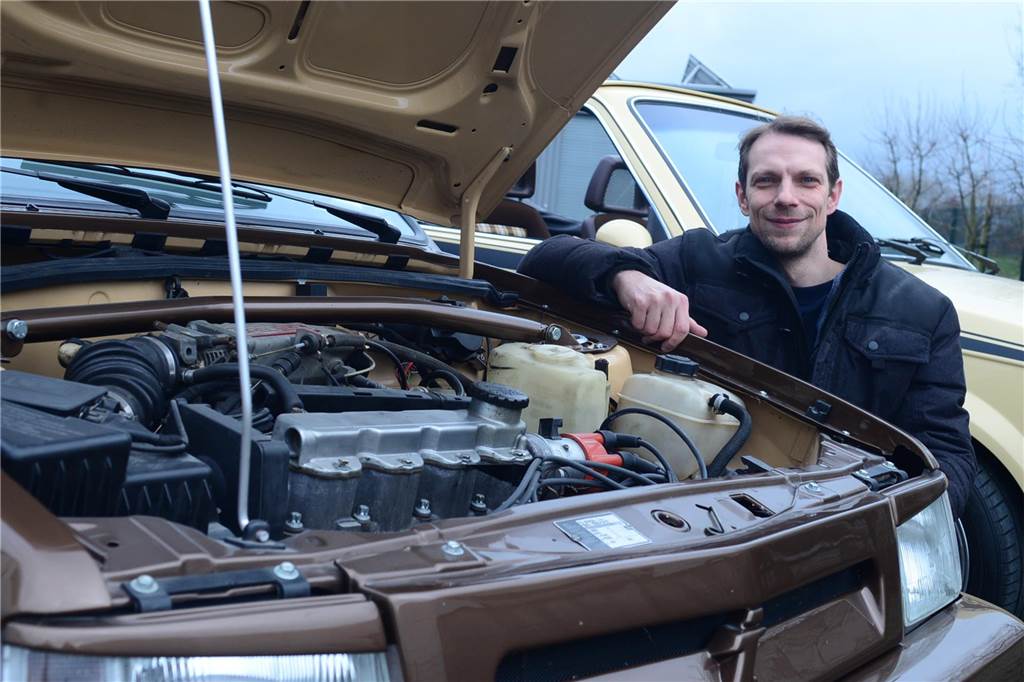 Echte Schrauber-Fans finden bei ihren Oldtimern immer einen Weg Denis Richarz kniet neben dem geöffneten Motorraum seines Opel Corsa A Spider Irmscher Cabrio.