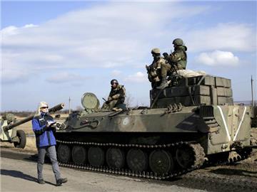 OSZE-Beobachterin vor ukrainischem Panzer. Künftig sollen deutlich mehr OSZE-Beobachter als bisher über den vereinbarten Waffenstillstand in der Ukraine wachen. Foto: Anastasia Vlasova