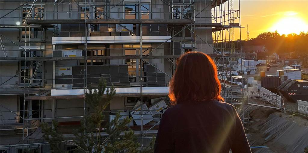 Urlaub auf einer Baustelle: „Traumzeit“ auf Usedom wird zum Horrortrip Eine Frau schaut vom Balkon ihrer Ferienwohnung auf Usedom bei Sonnenuntergang auf eine Baustelle.