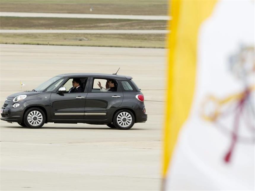 Papst und Obama vereint gegen Klimawandel und Armut Papst Franziskus verlässt in seinem Fiat 500 einen Flughafen nahe Washington DC, während im Vordergrund die vatikanische Flagge weht. Foto: Michael Reynolds