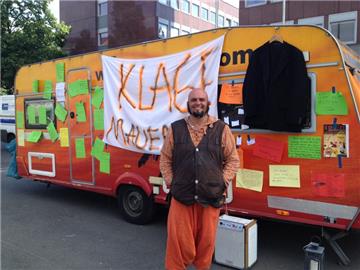 Pascal Thüer steht mit seinem Wohnwagen vor dem Jobcenter in Münster. Wer mag, kann Briefe an das Amt an die zur Klagemauer umfunktionierte Wohnwagenwand pappen.