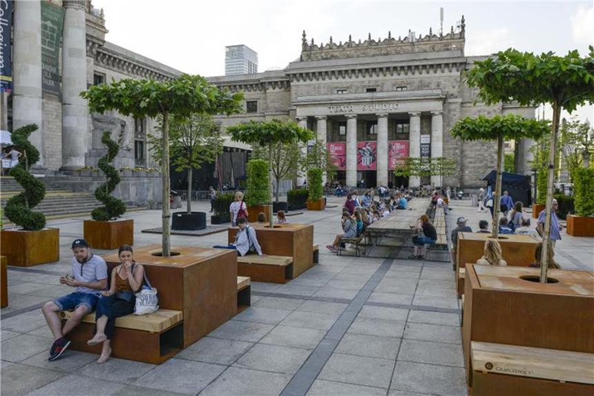 Passanten sitzen vor dem Kulturpalast inmitten verschiedener Bäume. Foto: XinHua