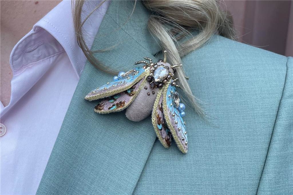 Outfit mit lustigem Detail: Marco und Patrick haben geheiratet Patricks linke Schulter ist zu sehen. Auf seinem grünen Anzug steckt eine Fliege als Brosche. Sie ist mit kleinen Steinchen verziert.