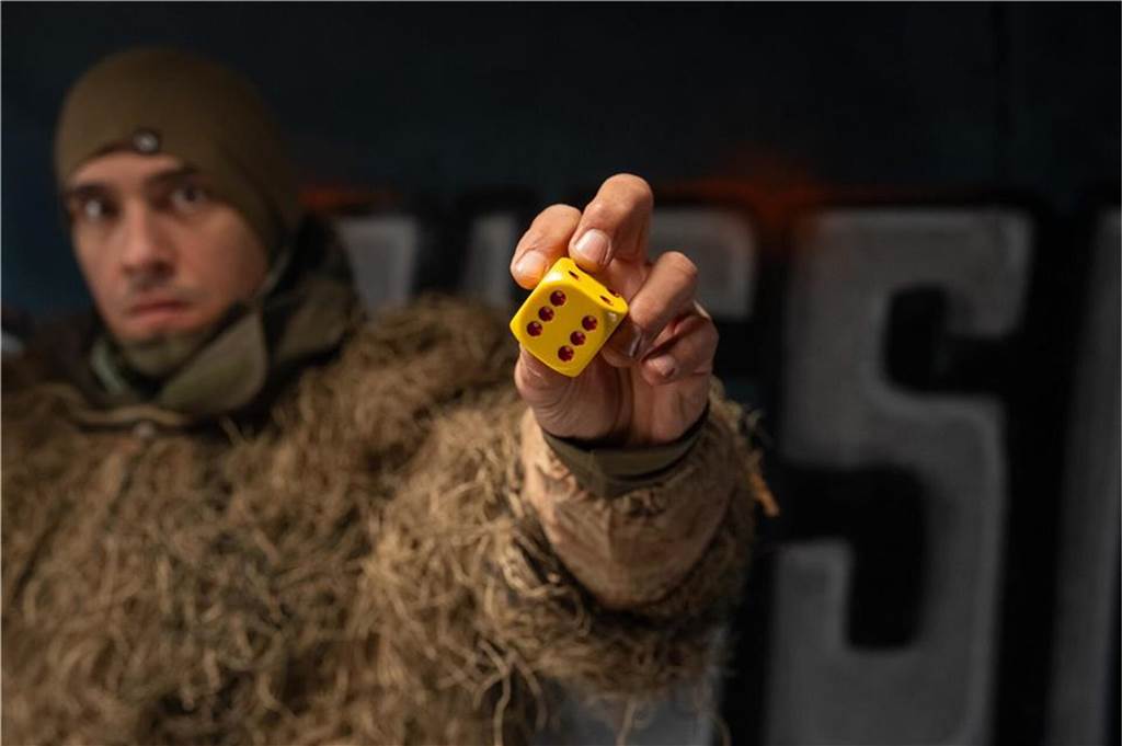 xx Ein Mann hält einen Spielwürfel in der Hand.