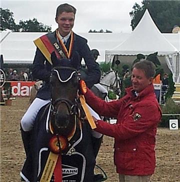 Peter Teeuwen, Bundestrainer der Ponyspringreiter, überreicht die Siegerschleife an Lars Volmer und High Noon.