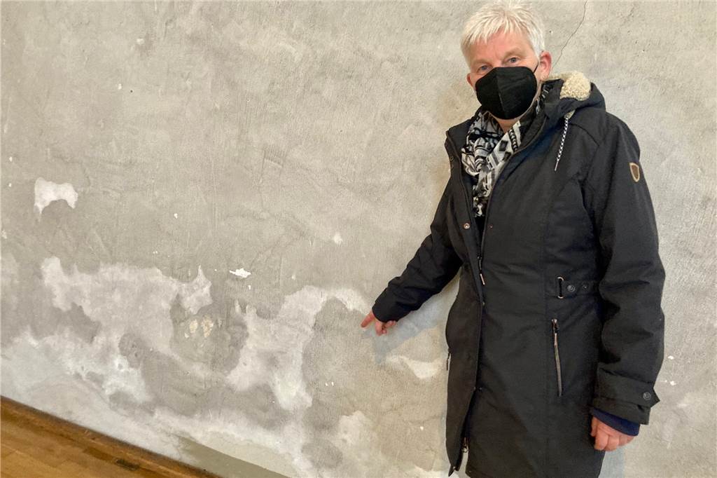 Pfarrerin Christel Schürmann zeigt die Schäden und Flecken an der Kirchenwand von St. Petri.