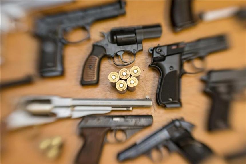Pistolen, Revolver und Munition auf einem Tisch in der gesicherten Asservatenkammer der Waffenbehörde eines Landkreises. Foto: Friso Gentsch