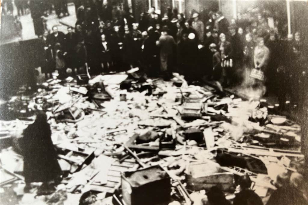 Ausgelöschtes jüdisches Leben: Nur steinerne Zeugen sind geblieben Historisches von der Pogromnacht - Menschen schauen auf Hausrat, der zerstört auf der Straße liegt.