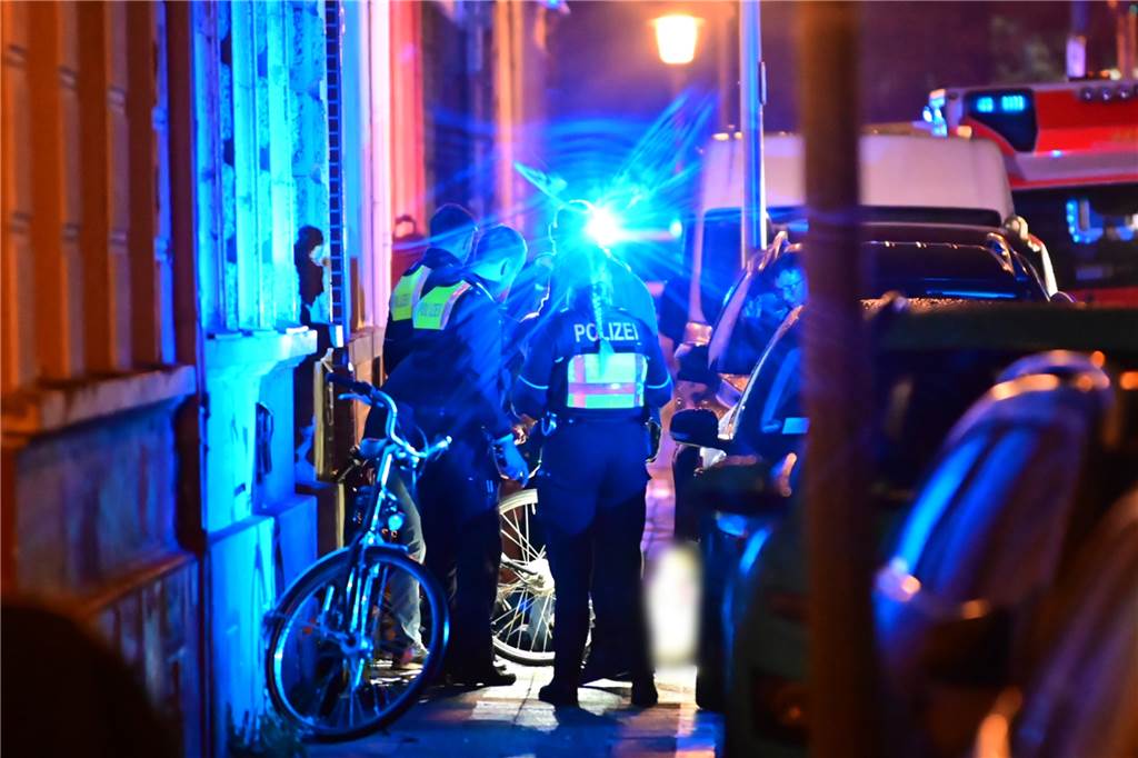 Mann in Krefeld auf offener Straße erschossen: Polizei fahndet nach zwei Verdächtigen Polizisten stehen auf einem Gehweg neben dem Toten.