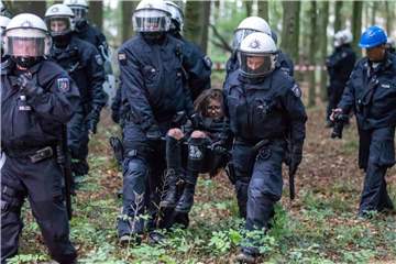 Polizisten tragen eine Umweltaktivistin weg. Foto: Christoph Reichwein