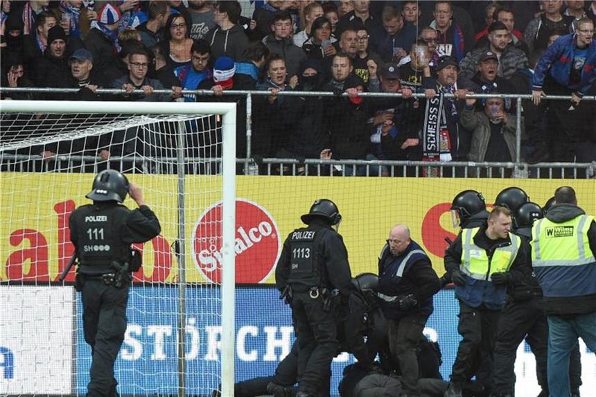 Schock nach Chaoten-Attacke in Kiel gegen St. Pauli Polizisten und Ordner halten Kieler Randalierer auf dem Rasen fest. Foto: Axel Heimken