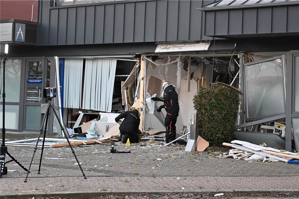 Zwei heftige Explosionen schrecken Anwohner auf: Geldautomat gesprengt Polizisten untersuchen den Tatort am Mittwochmorgen.