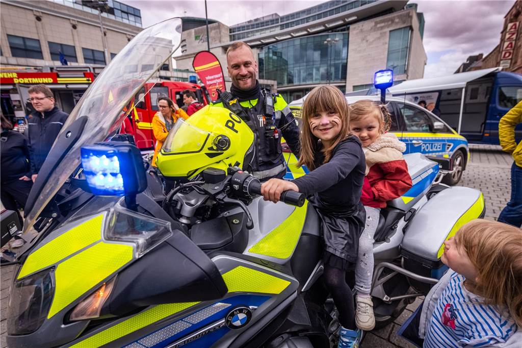 Zwei Kinder sitzen auf einem Polizeimotorrad.