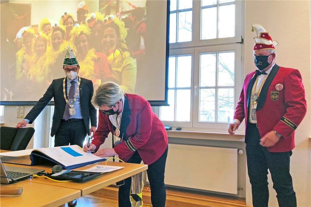 Altweiber in Stadtlohn: De-un-Da wird im Coronajahr nur geflüstert Prinzessin Susanne Hornhues und Prinz Manfred Schwenz tragen sich ins Goldene Buch der Stadt Stadtlohn ein; links Bürgermeister Berthold Dittmann.