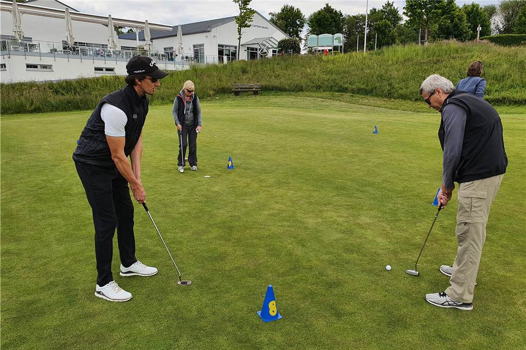 Schnupperkurs-Teilnehmer genießen Golfplatz-Atmosphäre trotz Corona-Einschränkungen Pro Julian Albers erläutert des Putten.
