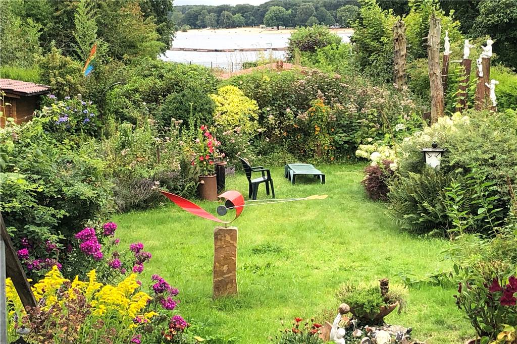 Das Haus am Halterner See: „Ich fühle mich wie ein Sonntagskind“ Rechts die Holzskulpturen als Wächter des Paradieses, vorn der idyllische Garten, im Hintergrund der Stausee: Jan und Ingmarie Visser hoffen, noch lange an diesem Fleckchen Halterns wohnen zu können.