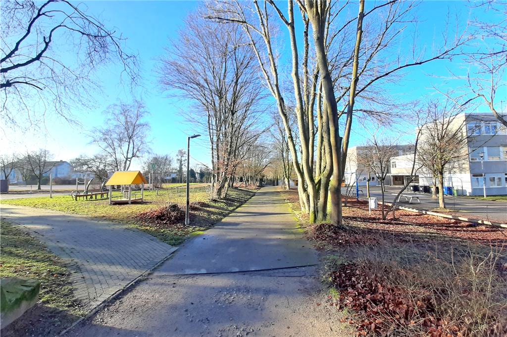 Rechts liegt die Johann-Gutenberg-Realschule Am Lieberfeld. Direkt links daneben die Lieberfeld-Grundschule – hier zu sehen mit dem Pausenhof und seinen Spielgeräten.