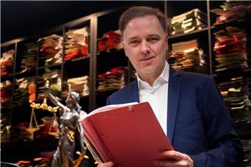 Rechtsanwalt Burkhard Benecken (46) im Podcast-Studio seiner Kanzlei in Marl. In der Hand hält er eine Prozess-Akte. Die Wände ringsum sind voller Fälle, die von den Anwälten der Kanzlei bearbeitet wurde.