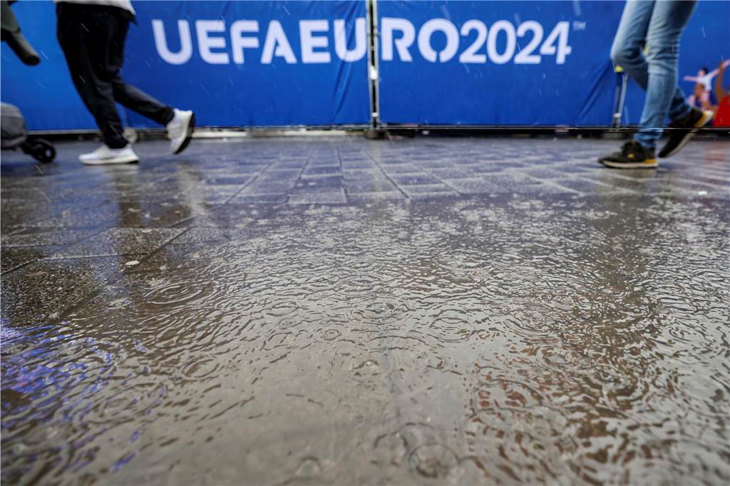 Unwetter über Deutschland: EM-Fanzonen geschlossen und Hurricane-Festival unterbrochen Regentropfen fallen in eine Pfütze beim Public Viewing in der Fanzone.