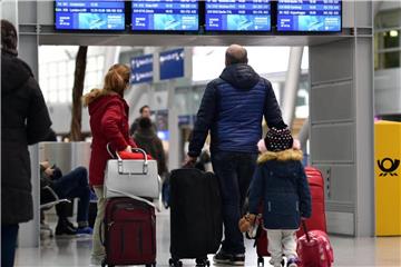 Reisende stehen im Flughafen Düsseldorf vor einer Abfluganzeigetafel. Foto: Caroline Seidel/Archiv